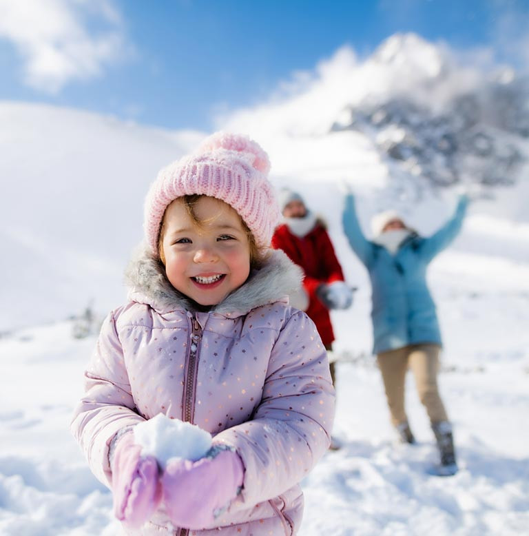Bimba che gioca con la neve su una montagna