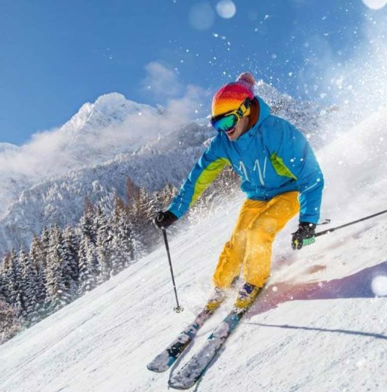 Uno sciatore che scende una pista innevata di montagna